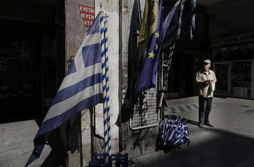 Un anciano ante una tienda que vende banderas griegas y de la UE en el centro de Atenas. Foto: EFE