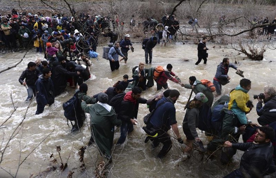 Los refugiados intentan cruzar de Grecia a Macedonia a través de un rio. Foto: EFE