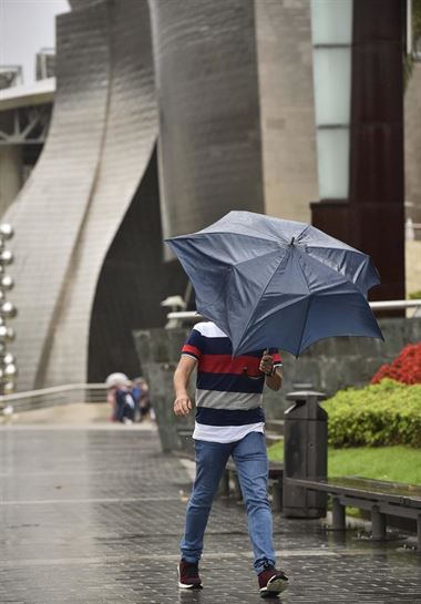 Un hombre lucha con el paraguas bajo la lluvia