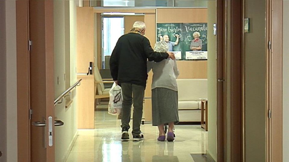 Dos pensionistas agarrados recorren un pasillo de Osakidetza