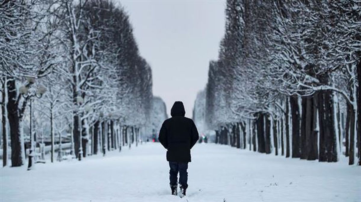 Una persona camina por París nevado. 