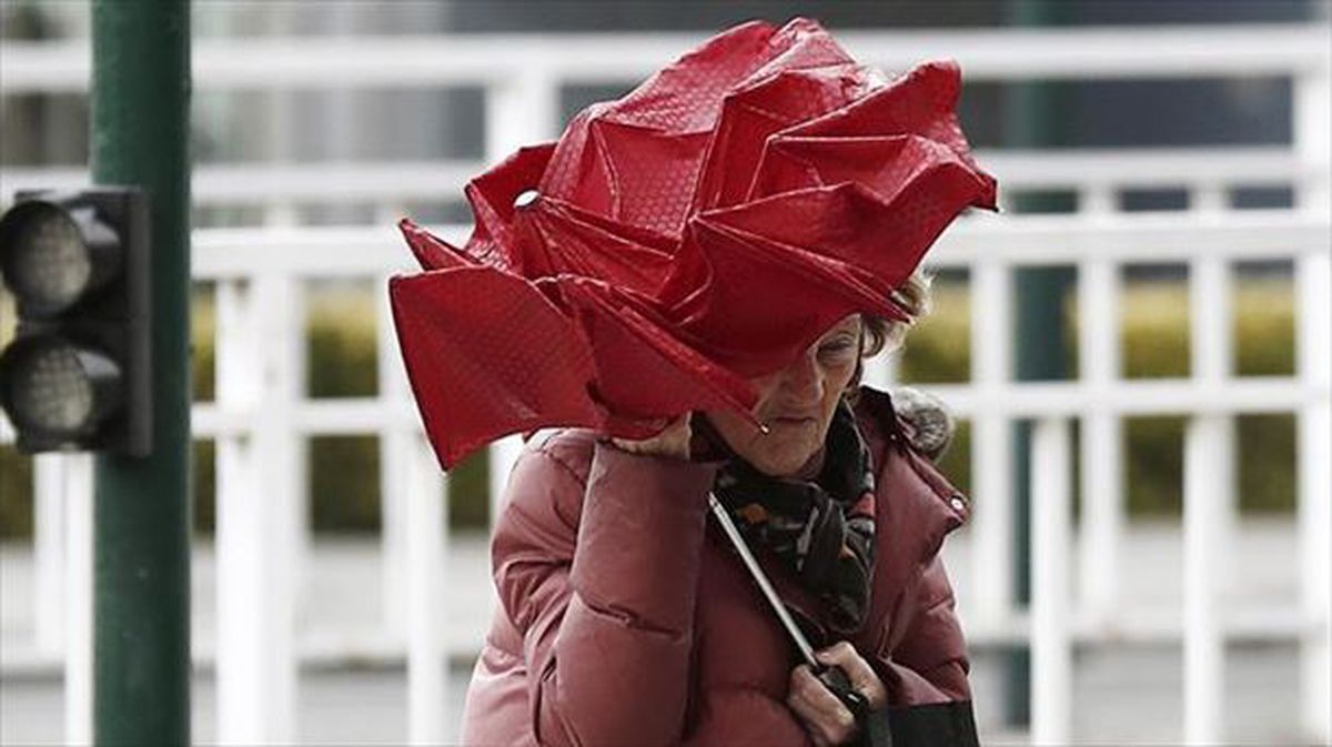Una señora se protege del viento en Pamplona.