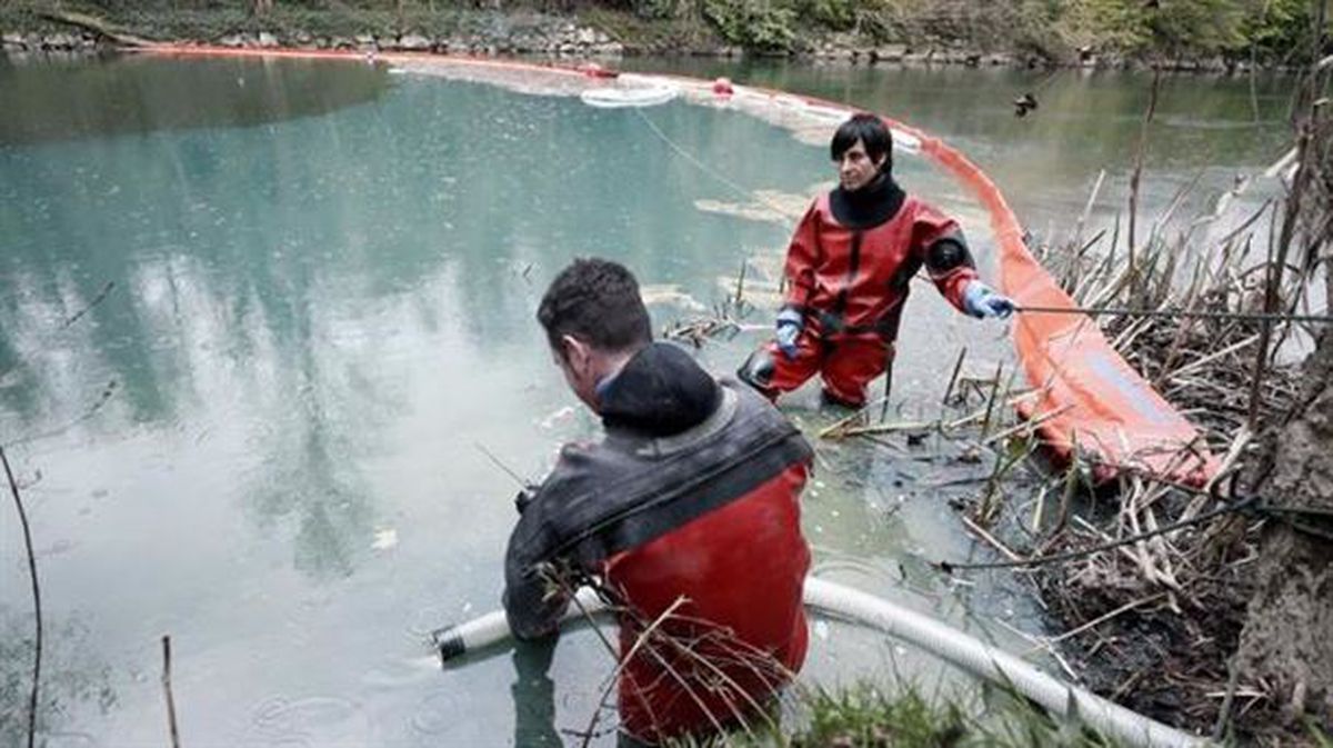 Bomberos succionan el gasoil que ha quedado retenido en una barrera colocada en el río Arga. EFE