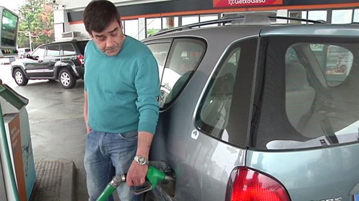 Un hombre reposa gasolina en una gasolinera de auto-servicio.