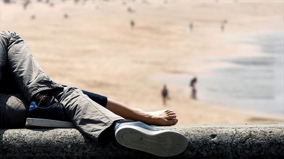 Una pareja descansa frente a la playa de la Zurriola. 