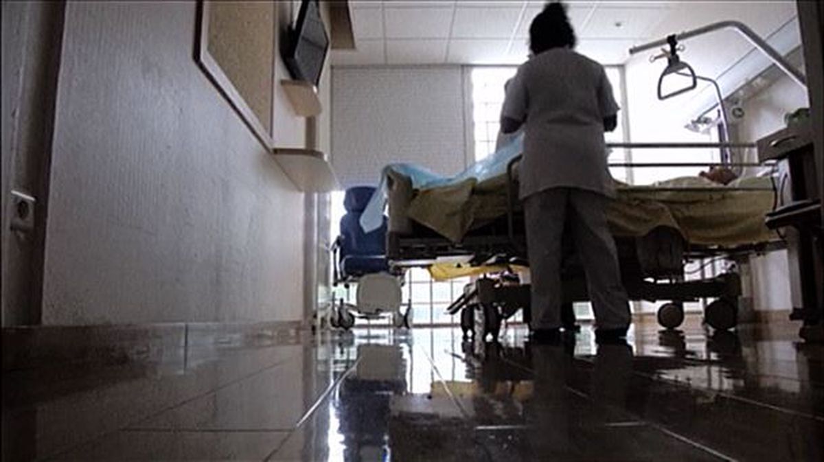 Una sanitario atiende a un paciente en el hospital. 