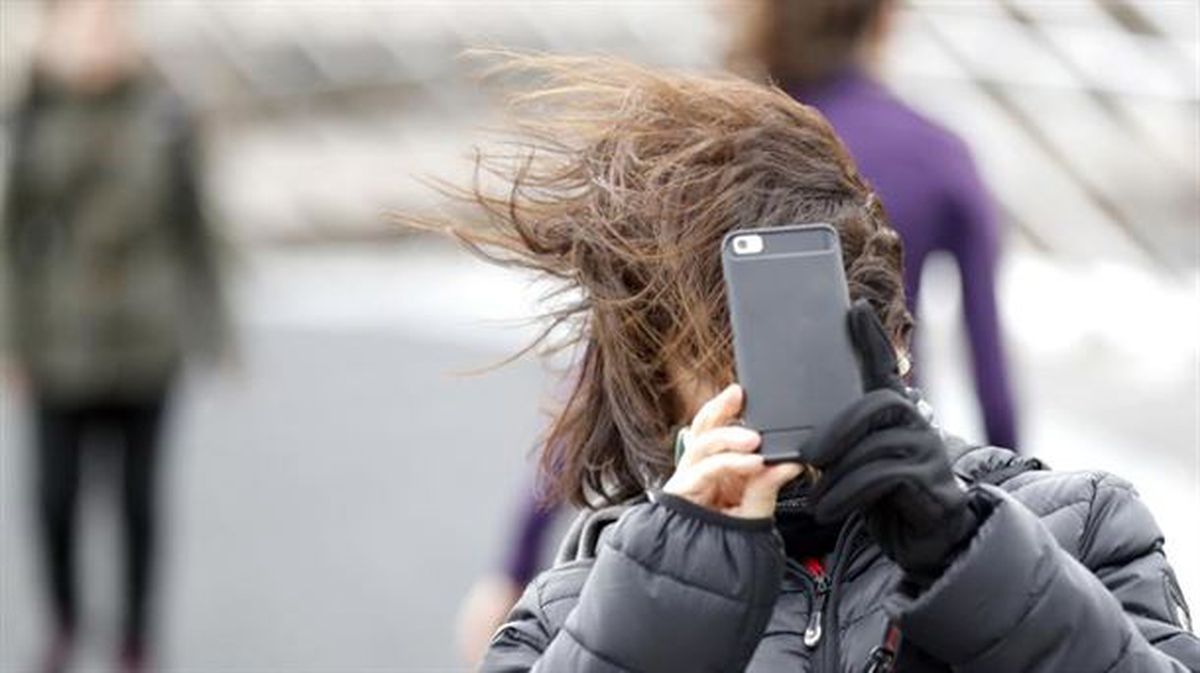 Una mujer intenta hacer una foto en Bilbao, un día de fuerte viento. 