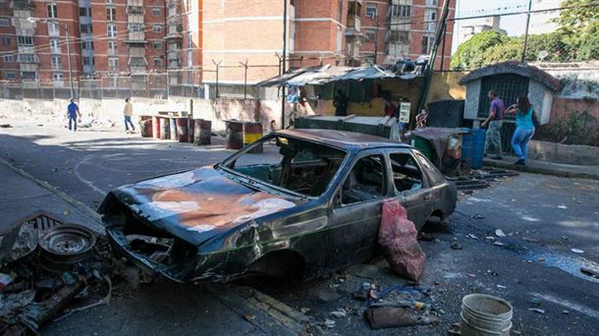 Restos de un vehículo incendiado en una calle donde hubo protestas este martes en Caracas