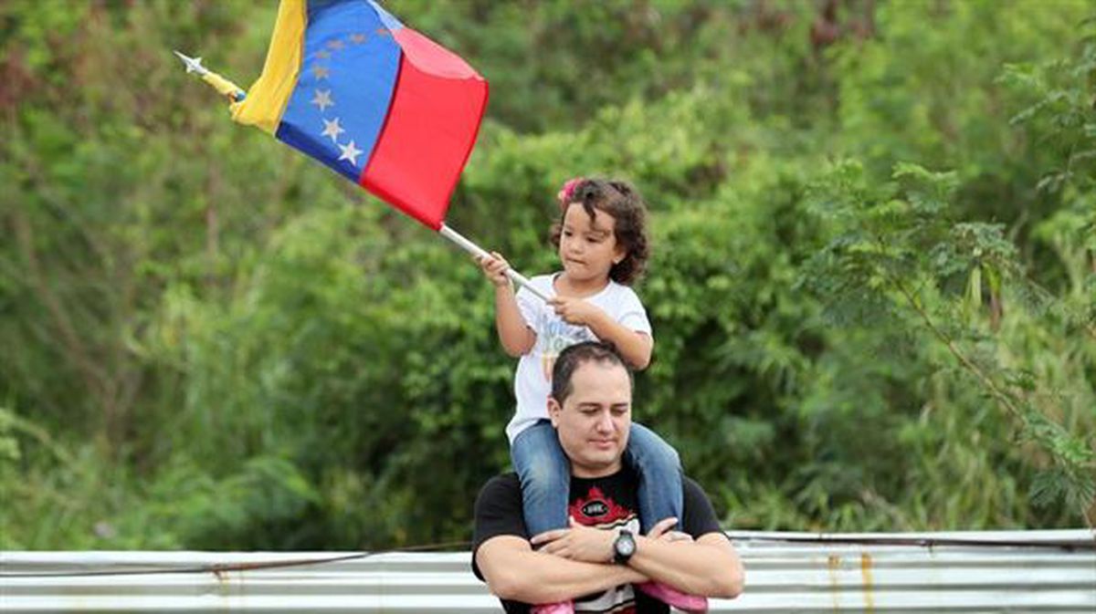 Un hombre carga a una niña que ondea una bandera venezolana este fin de semana