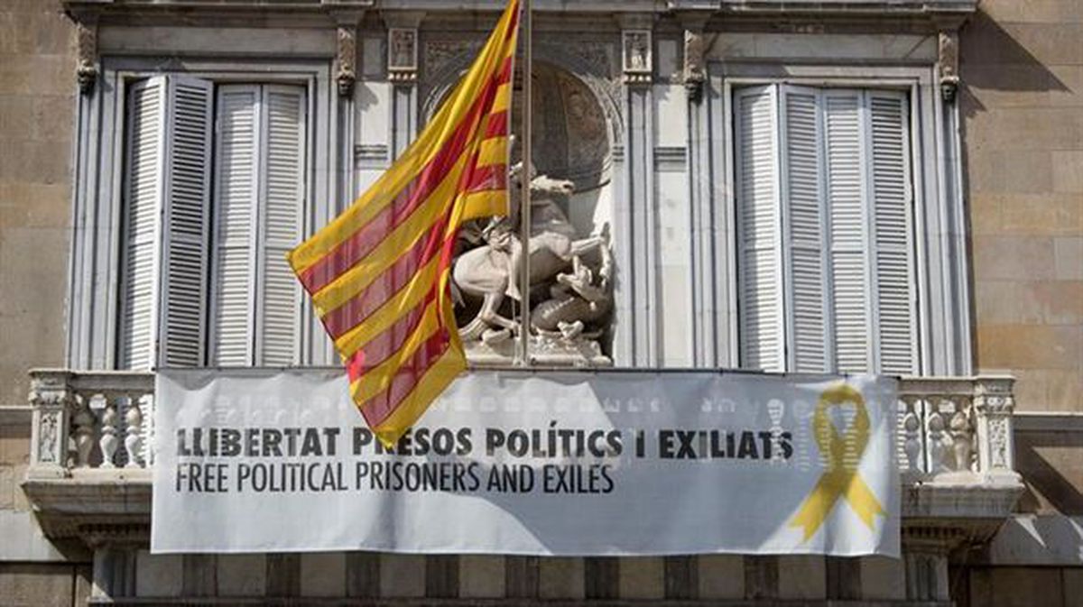 Estelada y un cartel con el lazo amarillo en la fachada del Ayuntamiento de Barcelona.