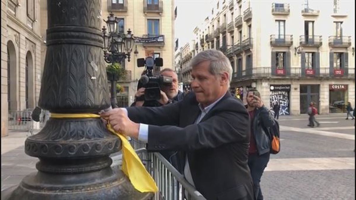 Un concejal del PP quita lazos amarillos de las farolas de la plaza de Sant Jaume