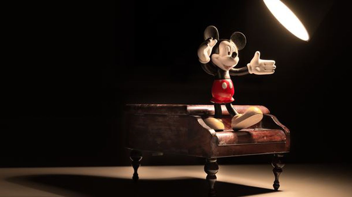 Un muñeco de Mickey sobre un piano bajo un foco