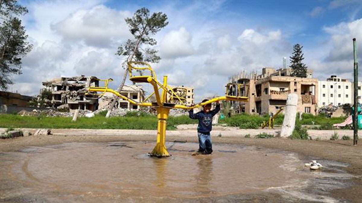 Un niño sirio juega en un parque inundado de agua en Al Raqa.