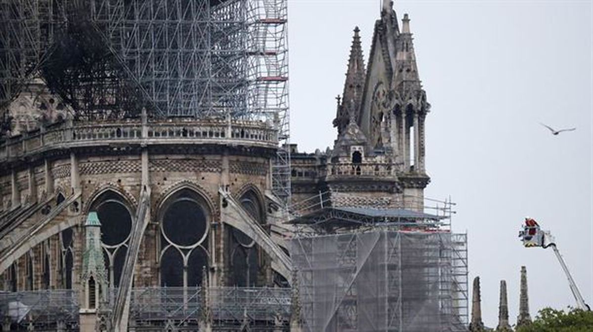 Bomberos sobre una grúa supervisan la catedral de Notre Dame de París.