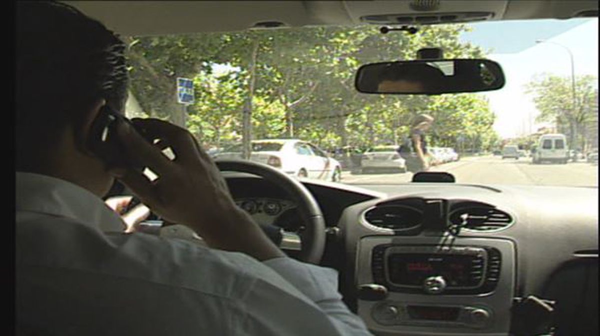 Un conductor al volante, usando el móvil
