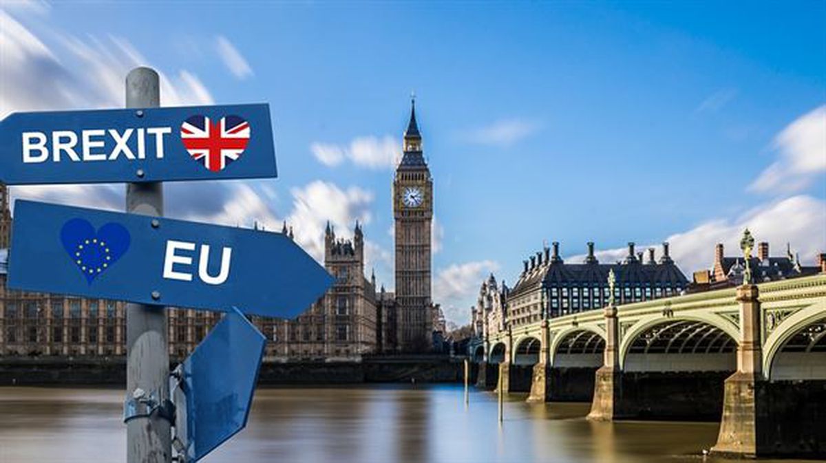 El Parlamento de Londres de fondo con dos carteles que señalan en direcciones opuestas 'brexit' y EU