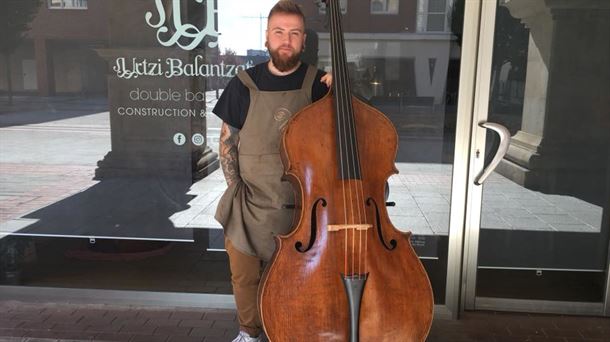 El luthier Urtzi Balantzategi en la puerta de su local en Leioa con uno de sus contrabajos