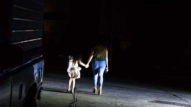 Una mujer y una niña caminan a oscuras por Maracaibo.