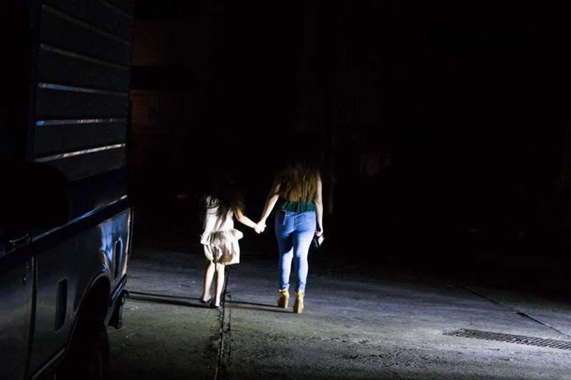 Una mujer y una niña caminan a oscuras por Maracaibo.