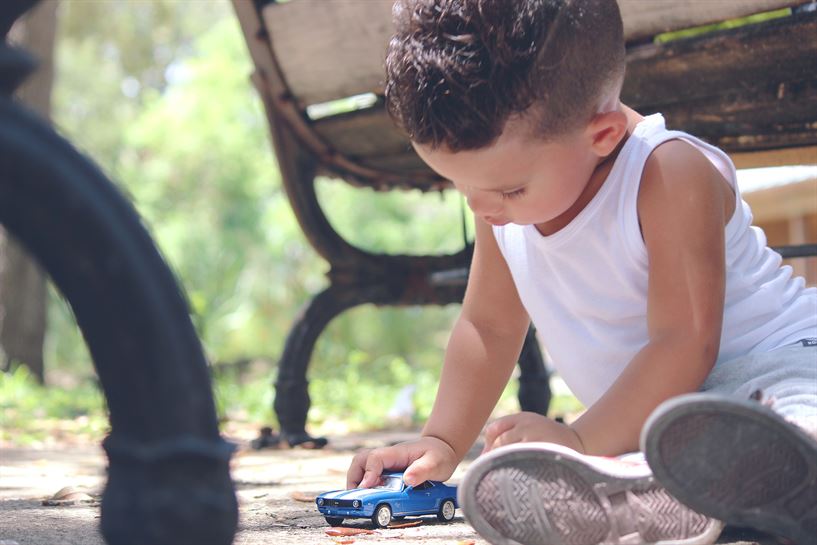 Un niño juega con un coche de metal