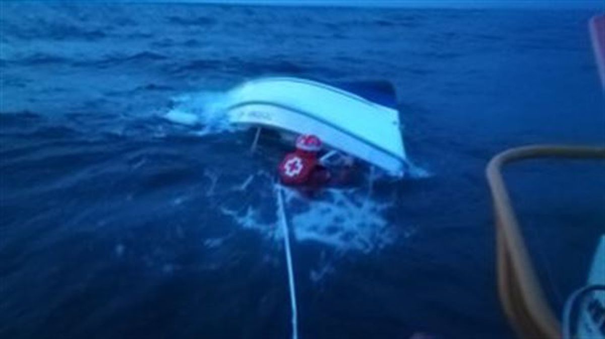 La embarcación prácticamente hundida siendo remolcada por un barco de rescate de Cruz Roja