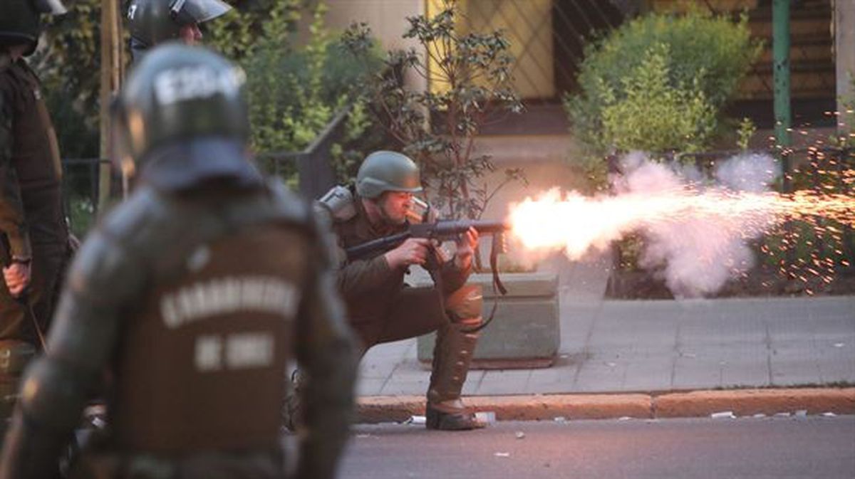 Un carabinero dispara bombas lacrimógenas contra manifestantes en Santiago. 