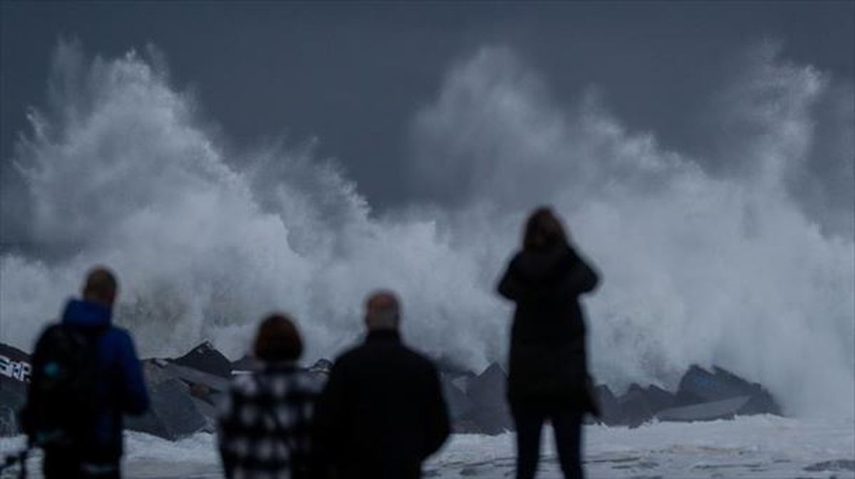 Varias personas observan las grandes olas en San Sebastián. 