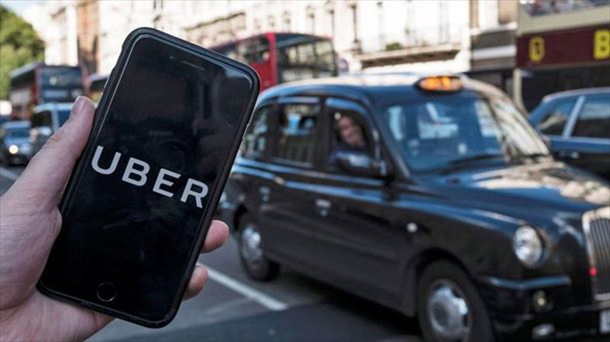 Una persona muestra la aplicación móvil de Uber ante un taxi en Londres.