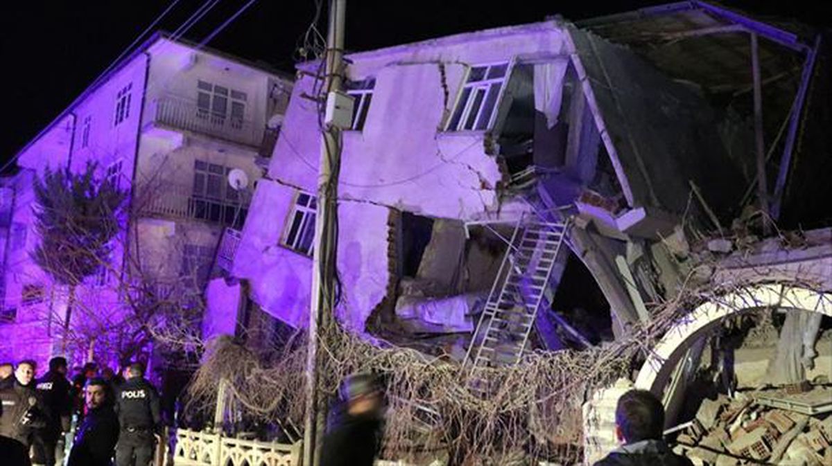 Vecinos y policías observan un edificio derrumbado por el terremoto.