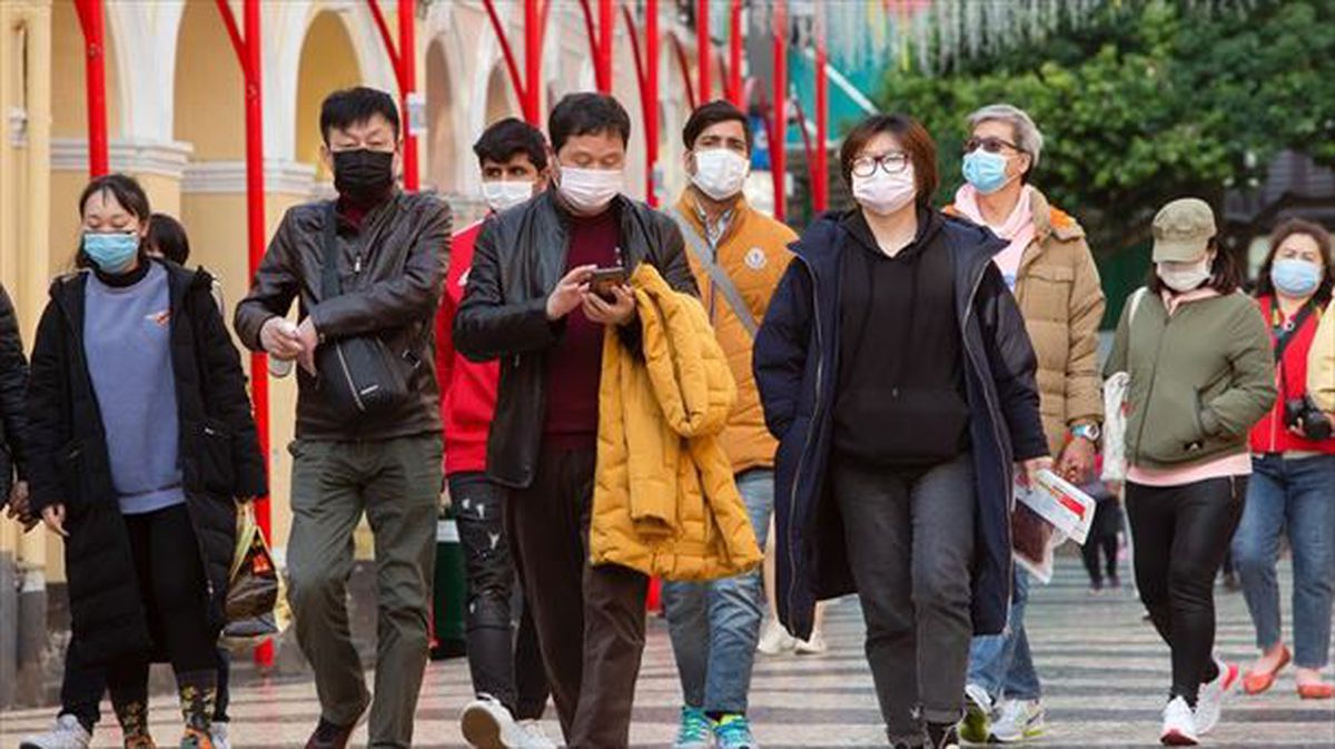 Un grupo de personas caminan por una calle de China con mascarillas contra el coronavirus (EFE).