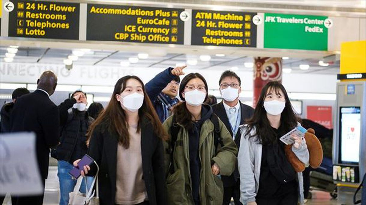 Un grupo de pasajeros con mascarillas en el aeropuerto JFK de Nueva York.