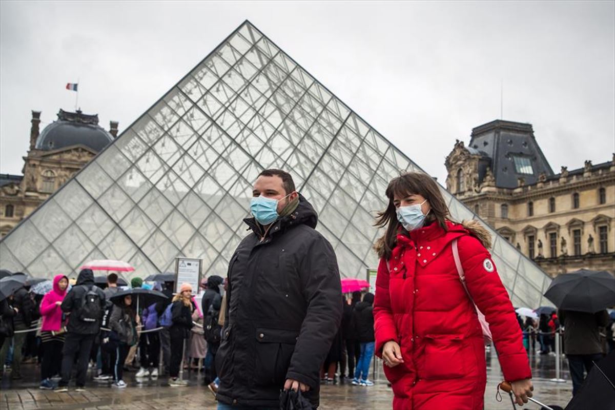 Visitantes con máscaras protectoras fuera de la pirámide del Museo del Louvre en París