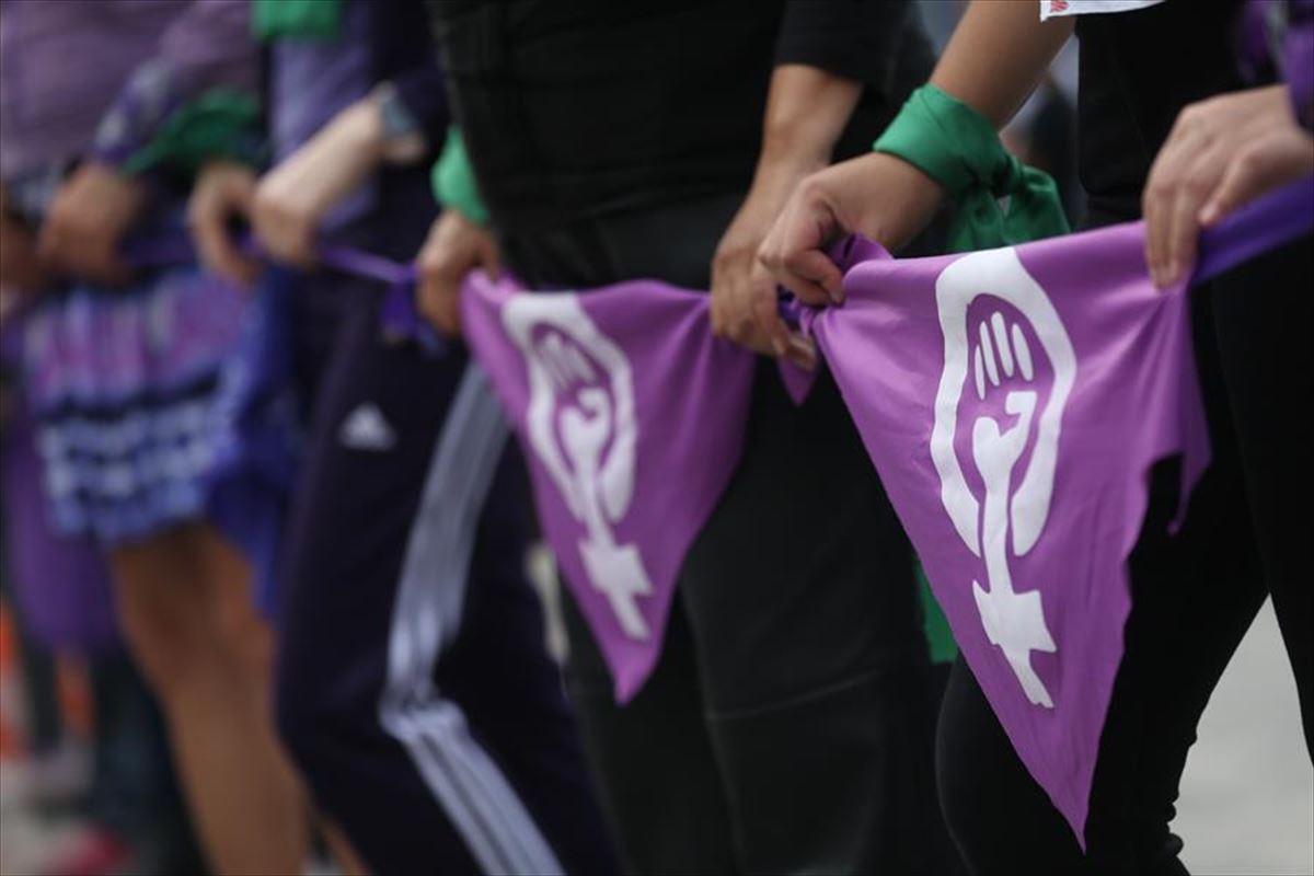 Dos mujeres portan sendos pañuelos con símbolos de la lucha feminista