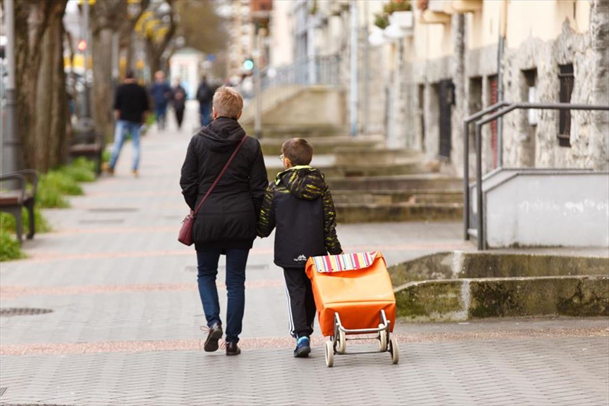 Un escolar acompaña a una mujer a la compra en Vitoria tras la clausura de la actividad docente. 