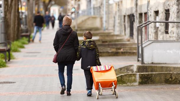 Un escolar acompaña a una mujer a la compra en Vitoria tras la clausura de la actividad docente. 