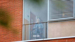 Imagen de una usuaria que mira por la ventana de una residencia durante el confinamiento. 