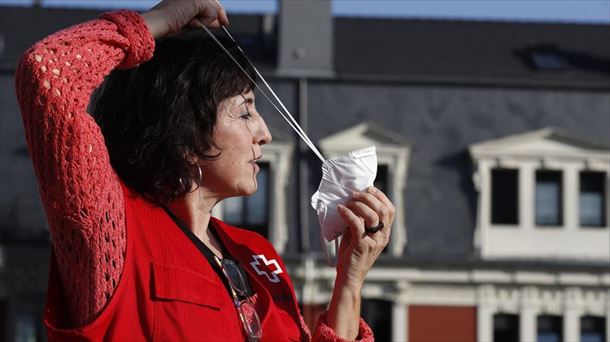 Una mujer se coloca una mascarilla para protegerse frente al coronavirus. 