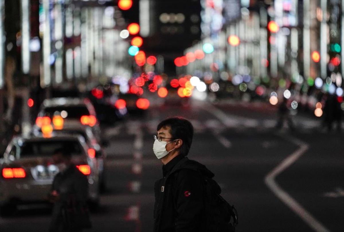 Un hombre con mascarilla pasea por una calle vacía de Tokio