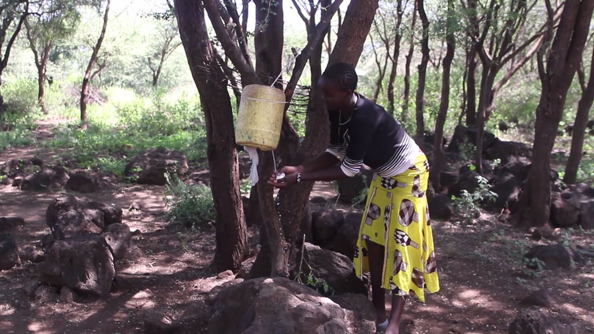 Una mujer africana, lavándose las manos con jabón.