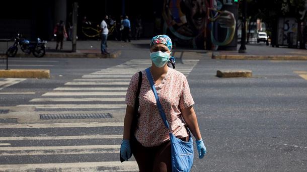 Una persona circula por la calle con guantes