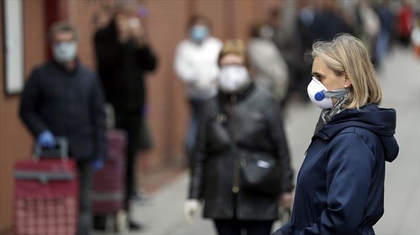 Varias personas, en una calle, con mascarillas