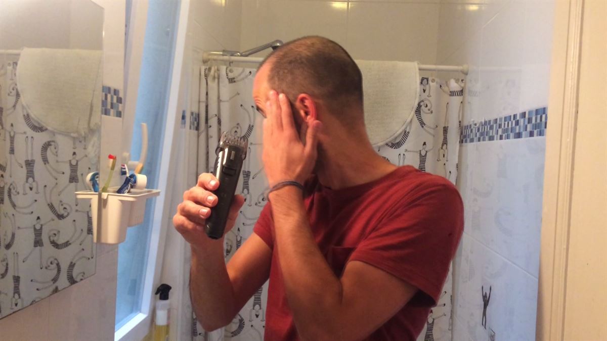 Imagen de una persona cortándose el pelo en casa.