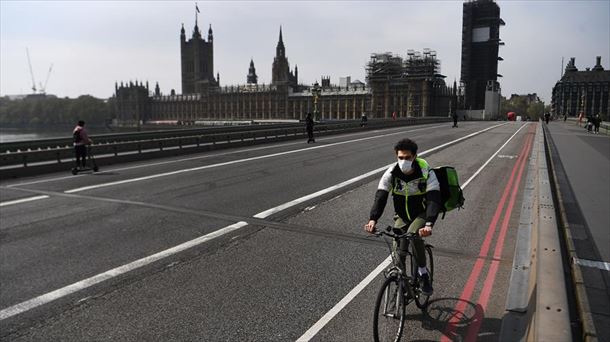 Una persona con mascarilla recorre Londres en bicicleta.