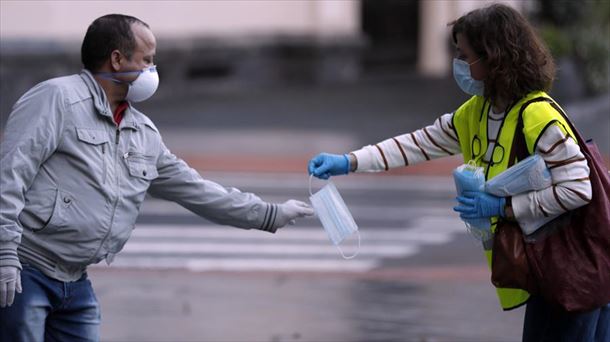 Una mujer dando una mascarilla a un hombre