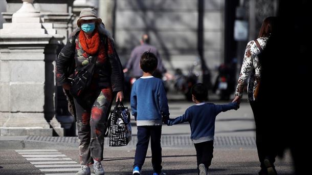 Dos niños pasean por la calle con un adulto