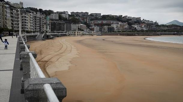 Un hombre pasea con dos niños este lunes en San Sebastián