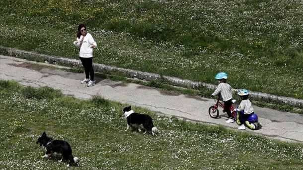 Emakume bat seme-alabekin eta txakurrekin paseoan, Iruñean