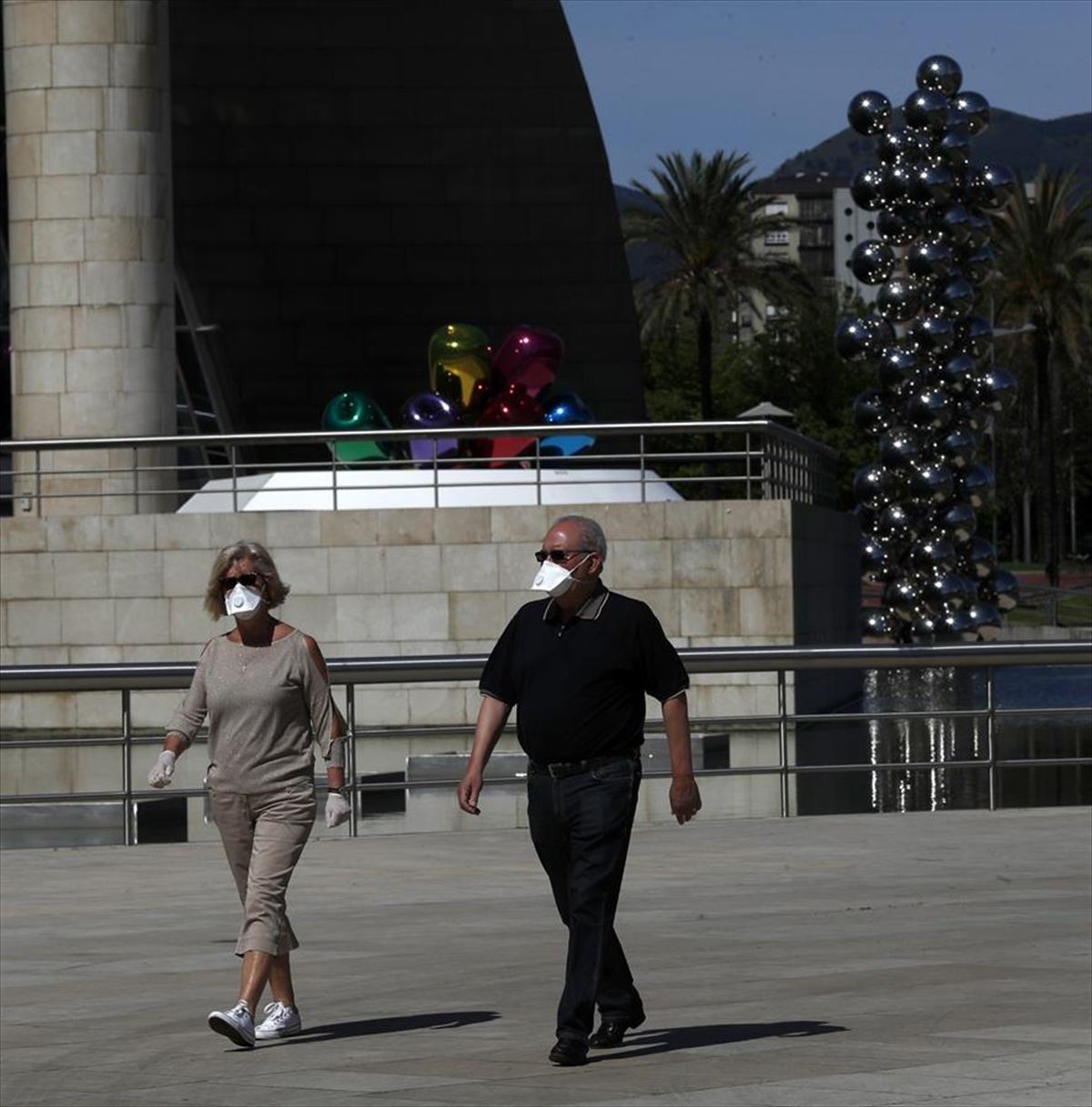 Dos personas caminan por Bilbao con mascarillas puestas.