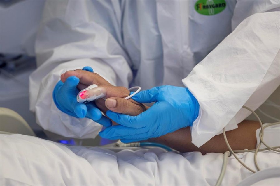 Un sanitario coge la mano a un paciente.