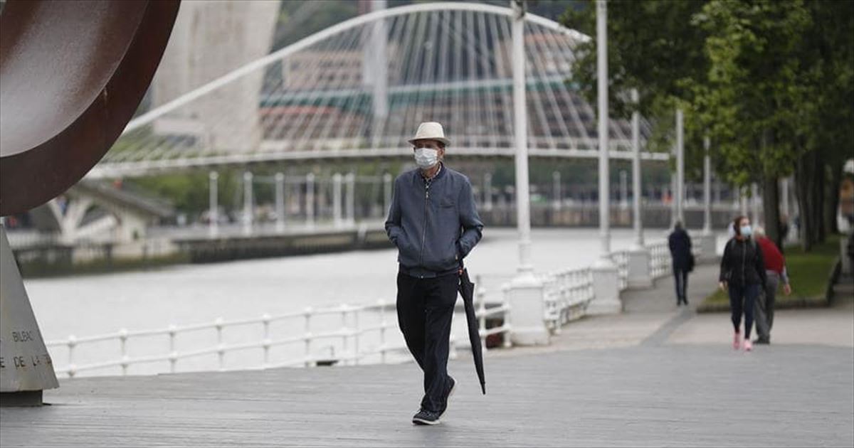 Una persona pasea por Bilbao protegido con una mascarilla